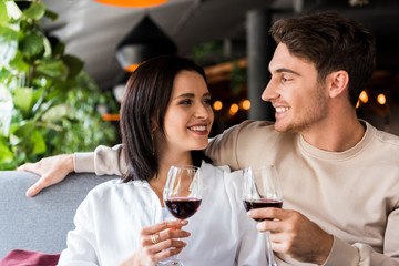 happy man and cheerful woman holding glasses with red wine