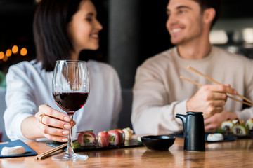 selective focus of girl touching glass with red wine near happy man