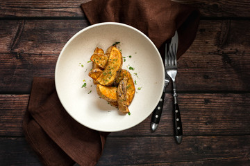 Roasted countryside styled potatoes on rustic dark wooden table
