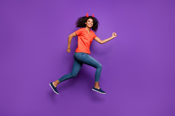 Fototapeta na wymiar Full length body size side profile photo of cheerful cute excited girl aspiring ahead for sales wearing jeans denim orange t-shirt smiling toothily jumping running isolated vivid violet color