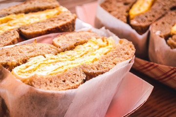 Freshly baked crunchy typical bagels with sesame, poppyseed topping and scrambled eggs from coffee shop or bakery in Manhattan, New York City, close up with selective focus.