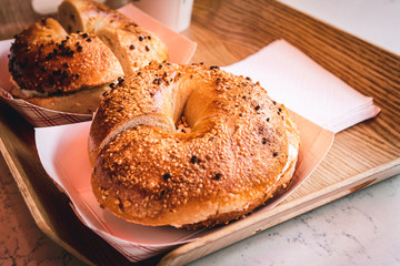 Freshly baked, crunchy typical NYC bagels with sesame, poppyseed topping, cream cheese spread and lox from coffee shop, cafe or bakery in Manhattan, New York City, close up with selective focus.