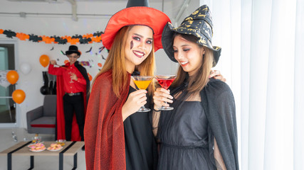 Halloween night 2 Beautiful young woman in witches hats and 1 man wizard costume in party Halloween  be joyful music and drink spooky trick and treat