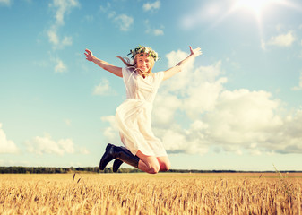 happiness, nature, summer holidays, vacation and people concept - smiling young woman in wreath of...