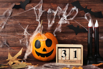 Halloween pumpkin with wooden calendar, dry leafs and paper bats