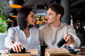 selective focus of happy man holding black napkin and looking at smiling woman