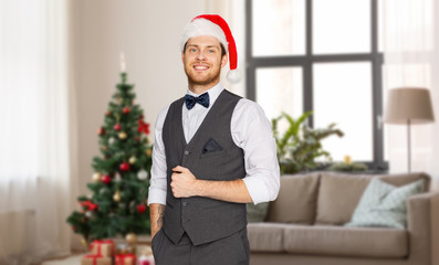 celebration, people and holidays concept - happy man in santa hat and suit over christmas tree on home background