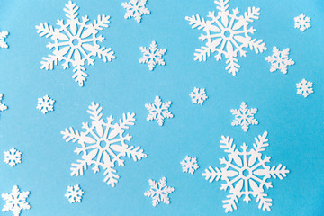 christmas, snow and winter holidays concept - white snowflake decorations on blue background