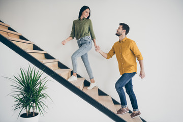 Let's explore this place. Full size profile photo of handsome guy and his pretty lady walking to bedroom go up stairs in just bought modern flat indoors wear casual clothes