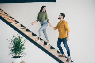Full length profile photo of handsome guy and his pretty lady walking to bedroom going up stairs in just bought modern flat indoors wear casual clothes