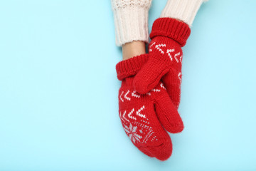 Hands in knitted mittens on blue background