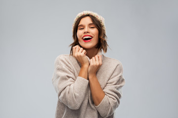 christmas, season and people concept - happy smiling young woman in knitted winter hat and sweater...