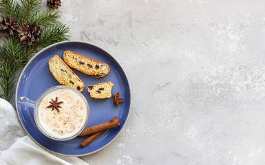 Eggnog. Christmas milk cocktail with cinnamon and anise, served in glass mug with biscotti, winter spices, fir branches and cones.