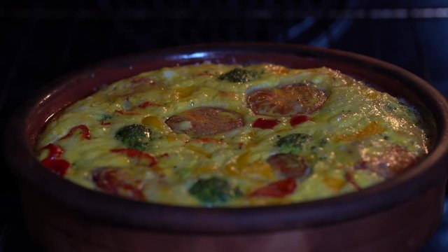 Ceramic bowl with vegetable frittata, simple vegetarian food. Frittata with egg, tomato, pepper, onion, broccoli and cheese , close up. Italian egg omelette in oven