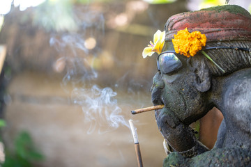 Traditional Balinese sculpture in sunglasses and a cigarette in the street . Island Bali, Indonesia . Close up