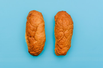 Naklejka premium Two fresh buns on a blue background. Tasty breakfast rolls. Bakery products.