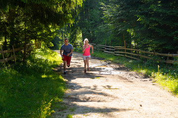 Obraz premium Running fitness couple of runners doing sport on road outdoor. Active living man and woman jogging training cardio in summer outdoors nature.