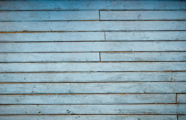 The wall of old house consisting of boards. Texture of old wood in a loft style. Old wooden wall beautiful light blue color. Horizontal boards.