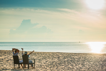 Couple Sitting On Chairs At Beach Against Sky