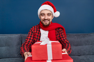 Smiling man giving Christmas gifts to camera