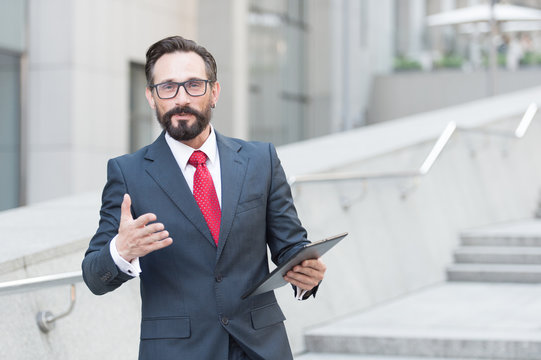 Waist Up Of Affluent Businessman Having A Talk With You While Holding A Tablet In Hand