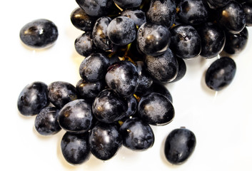 Fresh grapes on a branch lying on a white plate closeup