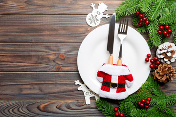 Top view of Christmas dinner on wooden background. Plate, utensil, fir tree and holiday decorations with copy space. New Year time concept