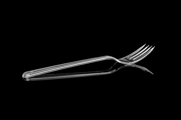 Transparent plastic fork isolated on black background
