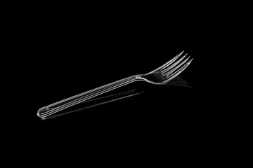 Transparent plastic fork isolated on black background