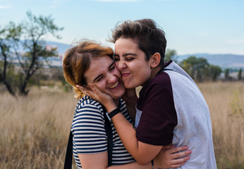 A lesbian couple is hugging in a meadow
