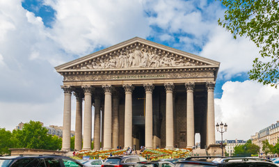 Fototapeta premium Full front view of the La Madeleine church with its Corinthian columns and sculptural pediment in Paris. It is built in the Neo-Classical style and the whole external form imitates a Roman temple.