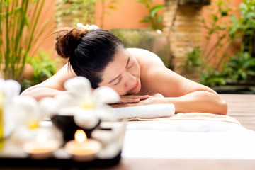 Fototapeta na wymiar Asian woman lying down on massage bed with scrub sugar and salt aroma at outdoor natural. wellness center, so relax and lifestyle. Thai Day Spa. Healthy Concept