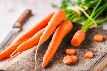 Ripe carrot top view on wooden board with knife. White background copy space.