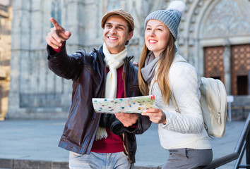 Man and woman with map and package looking attraction outdoors