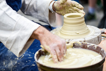 Man hands making ceramics ware. Modeling earthenwaredetail on potter's wheel. Creating vase or jar from white clay close-up.
