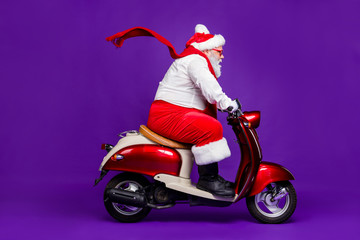 Photo of fat santa man grandfather rushing speed newyear x-mas theme party by bike wear sun spectacles trousers hat suspenders isolated purple background