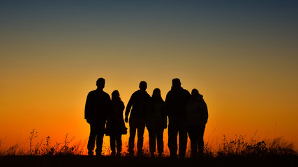 Three families silhouette gathering for a photo at sunset - 296572820