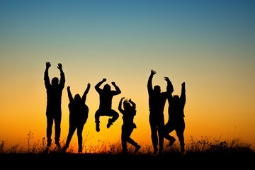 Happy people silhouette jumping in sunset