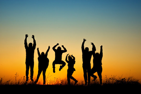 Happy people silhouette jumping in sunset