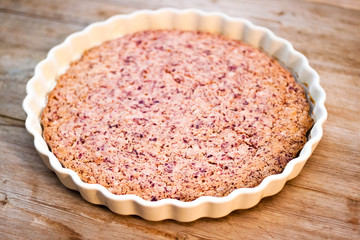 Cake or baked pudding of cottage cheese with red bilberry on white baking dish on wooden background