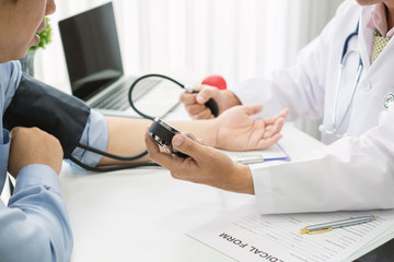 Doctor man is checking the blood pressure of the patient.