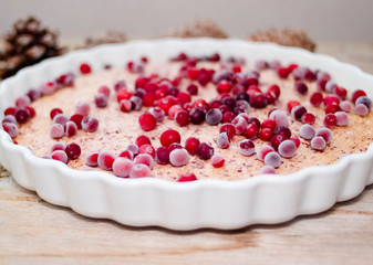 Cake or baked pudding of cottage cheese with red bilberry on white baking dish on wooden background