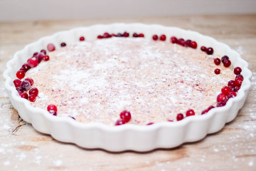 Cake or baked pudding of cottage cheese with red bilberry on white baking dish on wooden background