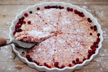 Cake or baked pudding of cottage cheese with red bilberry on white baking dish on wooden background