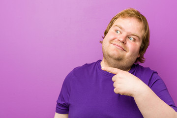 Obraz premium Young authentic redhead fat man smiling cheerfully pointing with forefinger away.