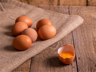 Chicken eggs and egg yolk in the shell lie on bags on wooden boards.