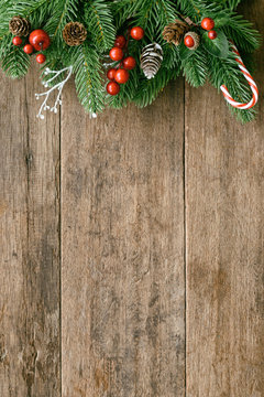 Wood table plank in vertical with pine leaves and pine cones, holly balls and candy cane in Christmas theme concept. Wooden background in top view flat lay with copy space for Christmas wallpaper.