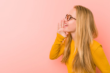 Adorable teenager woman shouting and holding palm near opened mouth.