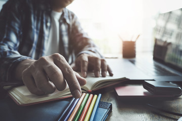 Young man working with color pencil and notebook and computer laptop for using design or creative  to drawing Draw clothes design. freelance at work concept.