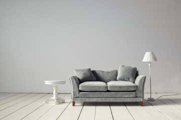 Comfortable grey sofa with table on light wall background